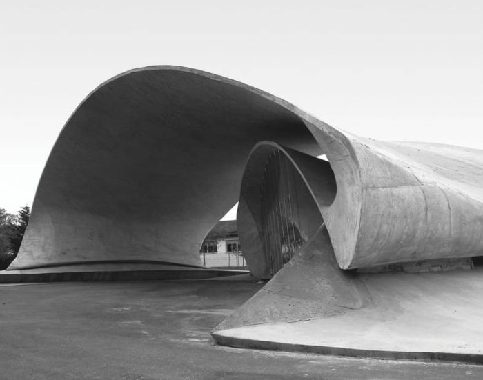bus stop in spain, made from concrete, with asymmetrical wave-like shapes, seen in a greyscale image