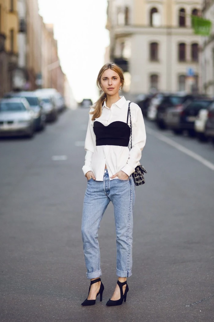 light blue jeans, and black high heeled shoes, worn by a young blonde woman, with a black, bustier style bralette, worn over a plain white shirt, bralette outfit ideas