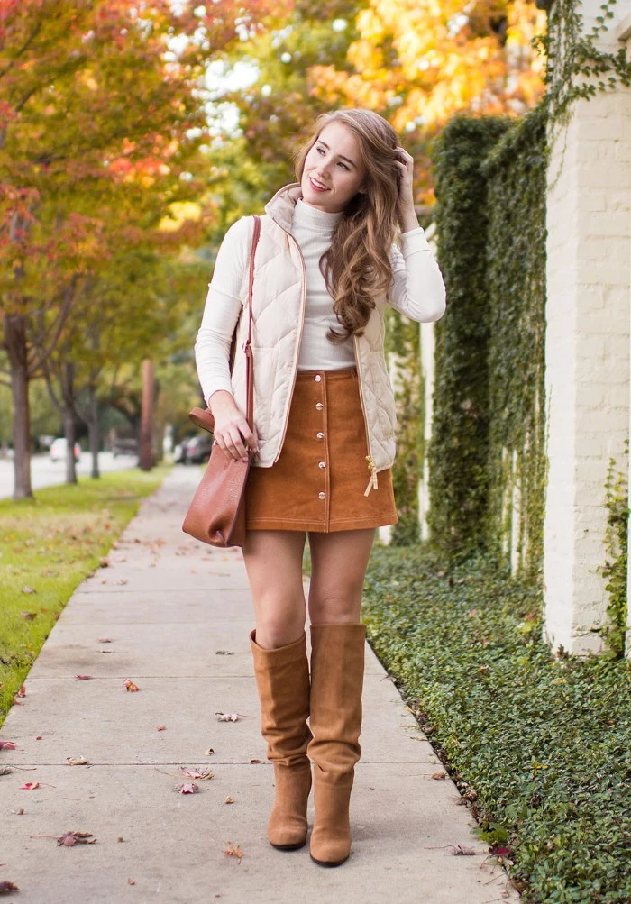 beige suede boots, and a button up mini skirt, in a similar color, worn with a white polo neck jumper, and a quilted cream gilet, thanksgiving outfits for women, on a smiling blonde woman, with long hair