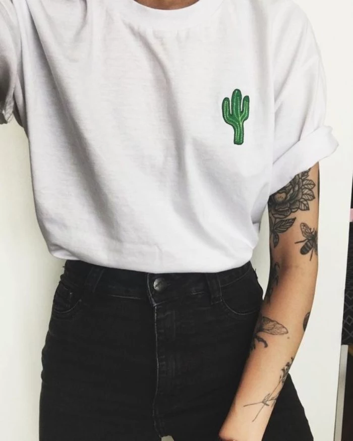 90s grunge fashion, oversized white t-shirt, with a small green cactus applique detail, worn tucked into black skinny jeans