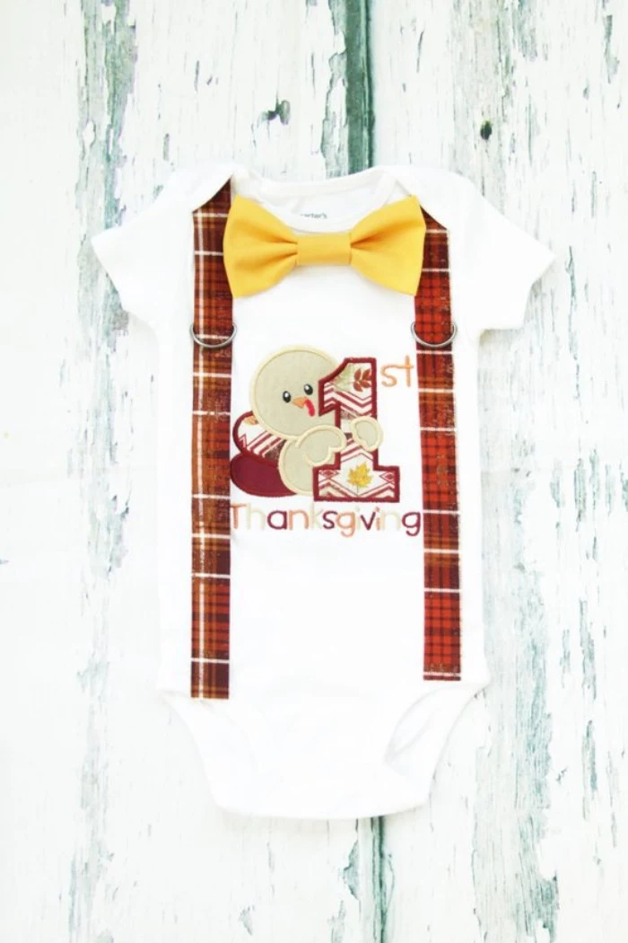 baby's first thanksgiving outfit, white onesie with short sleeves, featuring a cartoon turkey print, with the inscription 1st thanksgiving, yellow bow tie, and faux suspenders