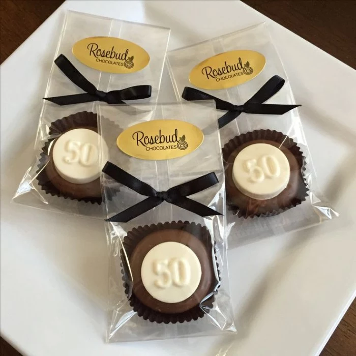 individually packaged brown and white chocolates, each featuring the number 50, and a black ribon tied in a bow, birthday party favors