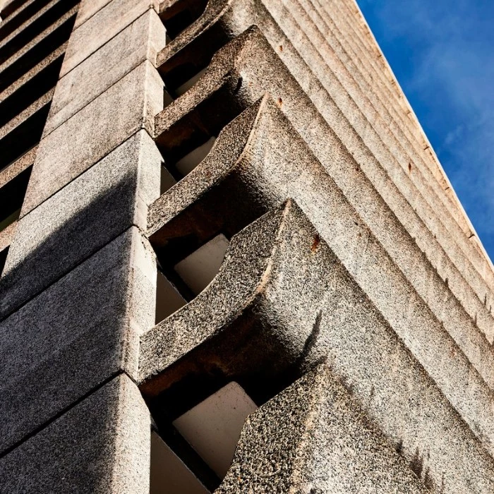 terraces made of concrete, on a tall building, seen in close up, brutalist architecture, blue sky in the background