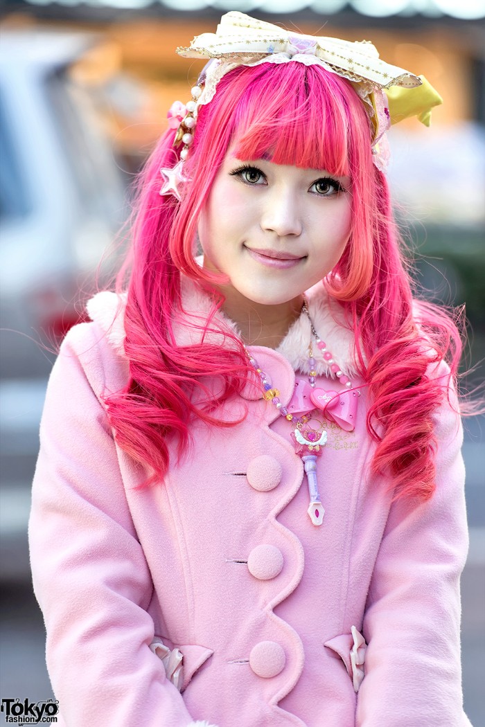 hot pink wig, with straight bangs and curls, on a smiling girl, dressed in a pastel pink, lolita fashion coat