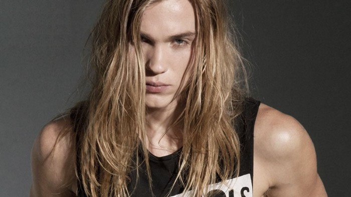messy and long blonde hair, on a pale young man, seen in close up, dressed in a black tank top, with white print, 90s bands and singers