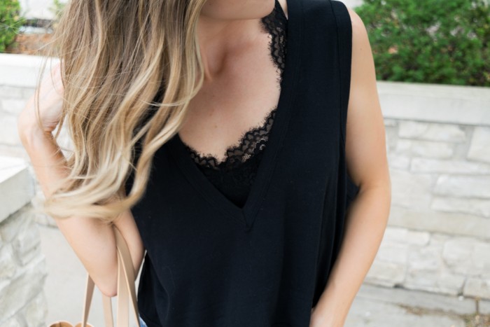 v-neck tank top in black, worn over a black lace bralette, by a woman with blonde ombre hair