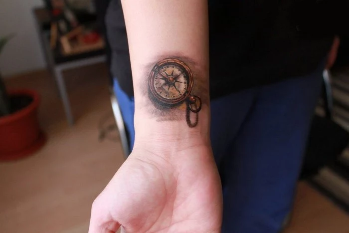forearm tattoos, compass in yellow and grey, seen in close up, tattooed on a person's wrist