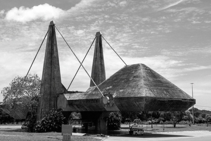 centro de exposições do centro administrativo da Bahia, in bahia brazil, large dark concrete structure, suspended in the air, by big metal ropes, tied to two columns
