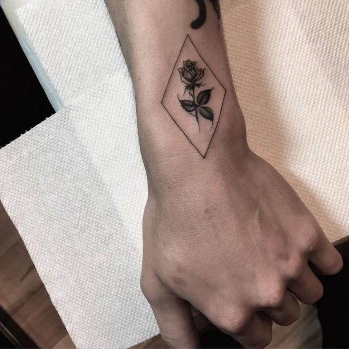 diamond shape drawn in black, containing a rose, with four leaves, forearm tattoos, on the upper side of a man's wrist