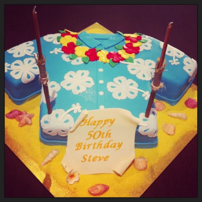 cake shaped like a shirt, pale blue with white floral hawaiian-style print, and a flower garland made from yellow and red fondant, 50th birthday colors, for a hawaiian themed party