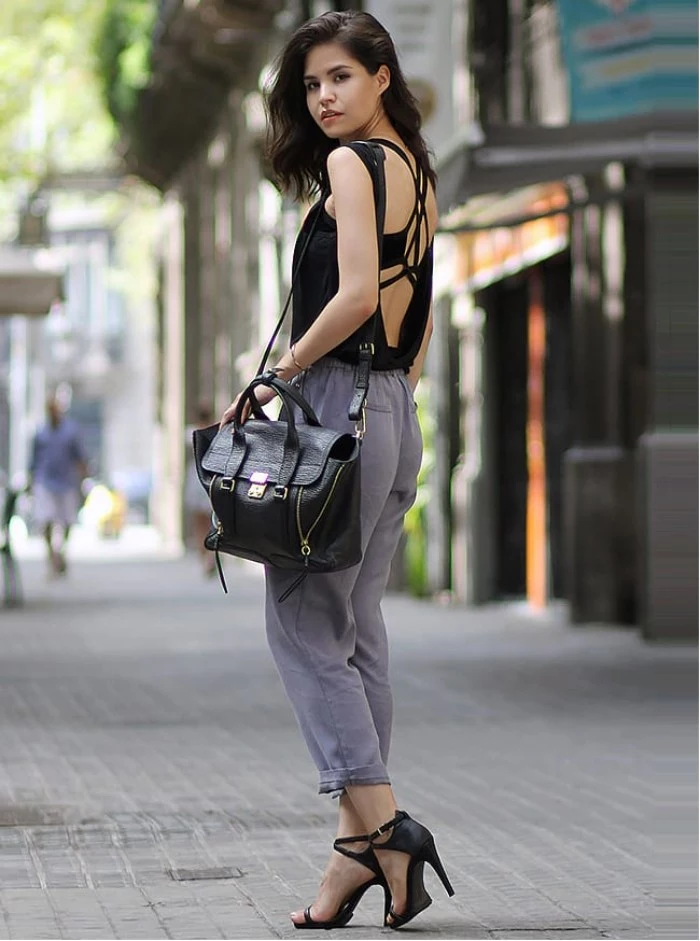 open back top in black, worn over a black bralette, with crossing straps, by a brunette woman, what is a bralette, light grey ankle trousers, black high heel sandals