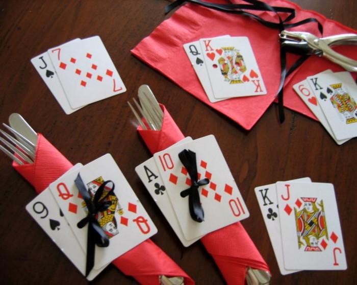 forks and knifes, wrapped in red paper napkins, decorated with playing cards, tied to them with black ribbons, 50th birthday party ideas for men, table set up and decorations