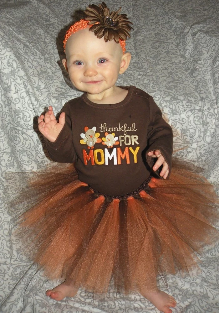 baby girl thanksgiving outfit, brown jumper with orange and beige, yellow and white embroidery, and a brown and orange tutu skirt, on a smiling dimpled baby