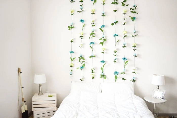 bright room with white walls, a white bed, and two bedside tables, diys for girls, featuring a wall decoration, made from multiple fake flowers, stuck together to form seven columns