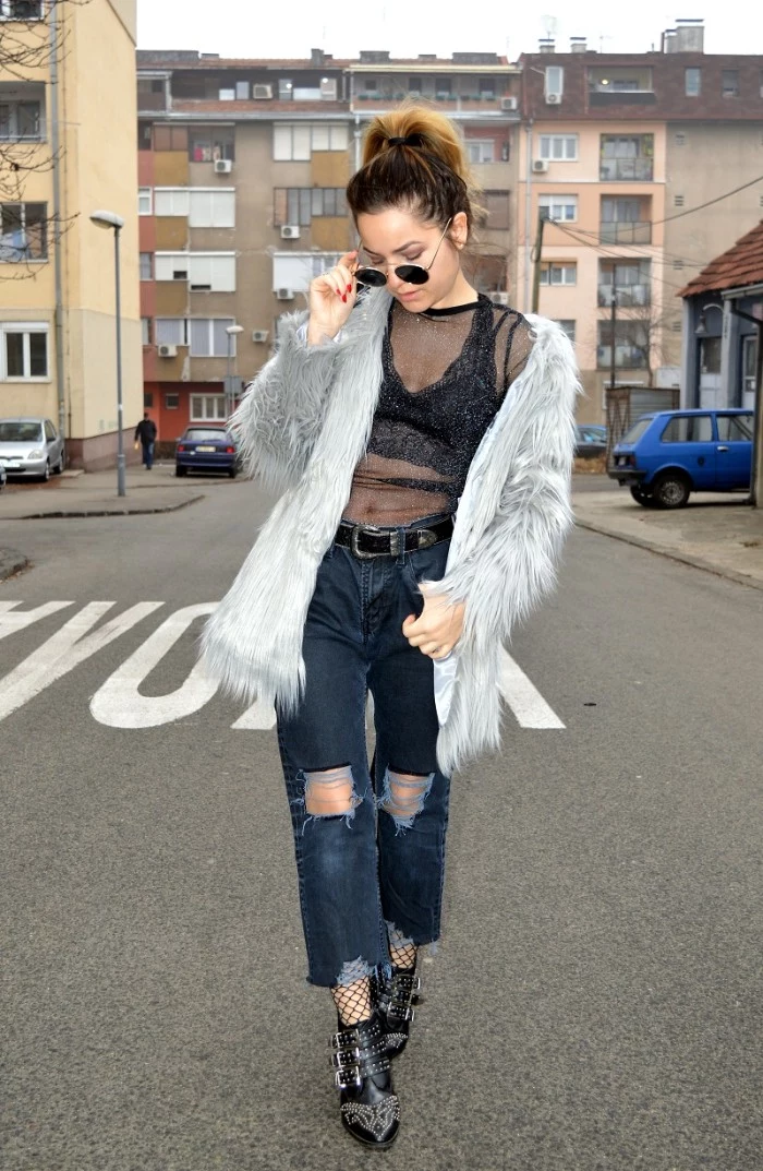 what is a bralette, woman in a grey, faux fur coat, ripped dark blue, wide fit ankle jeans, a sheer black top, and a black bralette