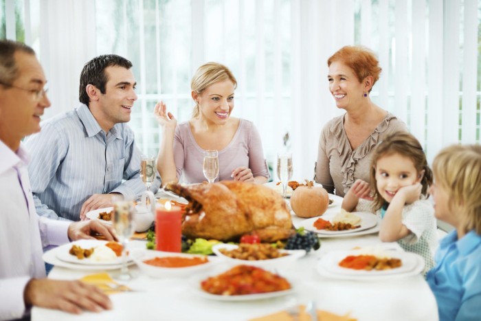 parents and two children, and two grandparents, sitting around a table, thanksgiving text messages, roasted turkey and other dishes