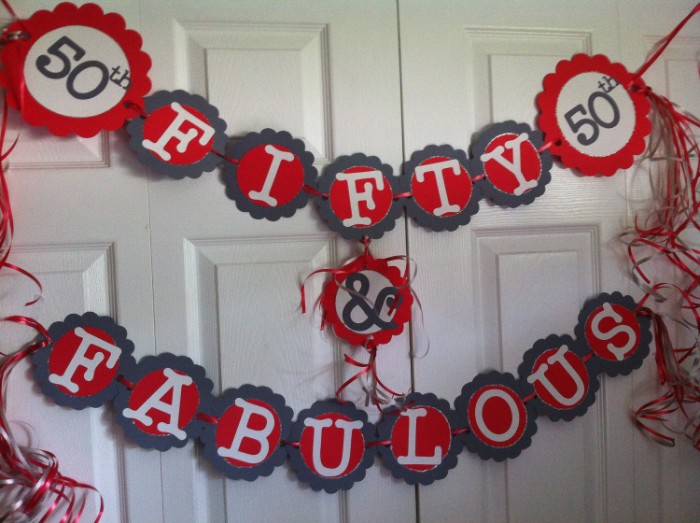 streamers and garlands, in red and dark grey, white and black, featuring the words, 50th fifty & fabulous, decorating a white door