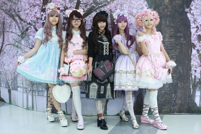examples of the gothic and sweet lolita styles, five girls in different lolita dresses, pale blue and pink, black and light violet, multicolored with frills and cutesy pattens