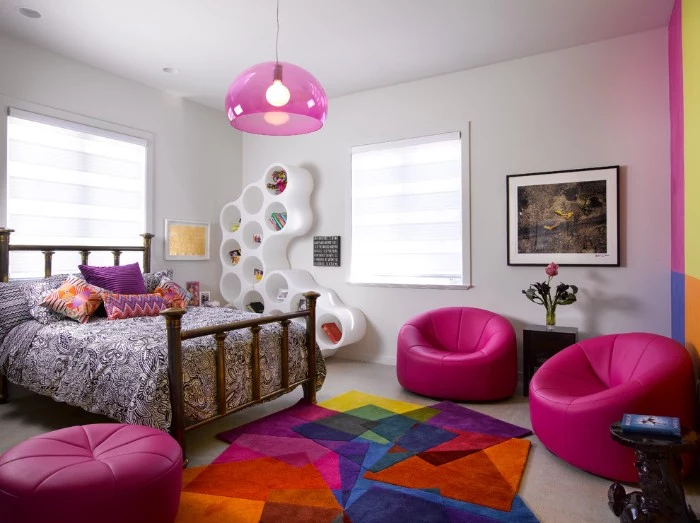ottomans in fuchsia pink, in a room with a bed, covered in multicolored cushions, cute teen rooms, multicolored rug and a framed painting