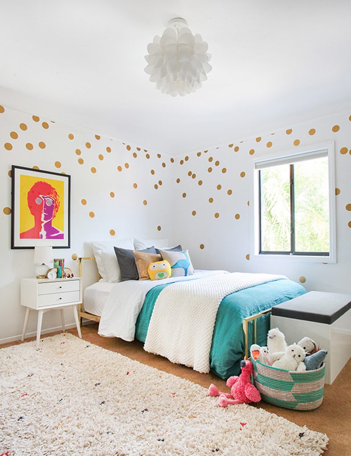 pop art style image, in a black frame, hanging on a white wall, decorated with gold dots, in a room with a bed, a window and a fluffy pale beige rug