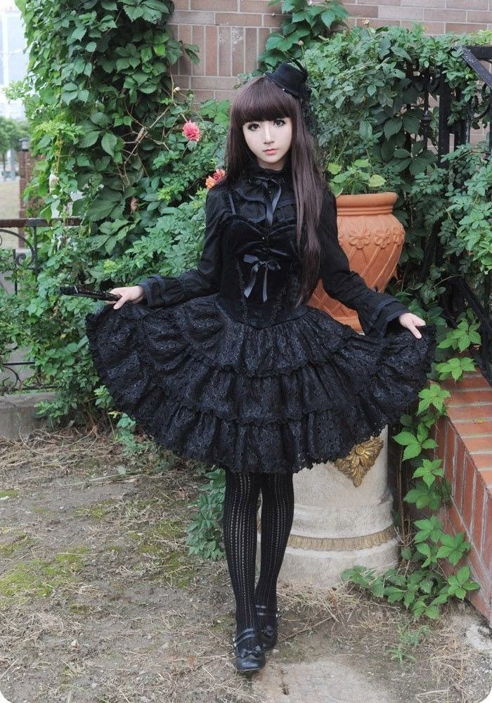 black frilly dress, with a velvet corset detail, worn by a pale girl, with long brunette hair