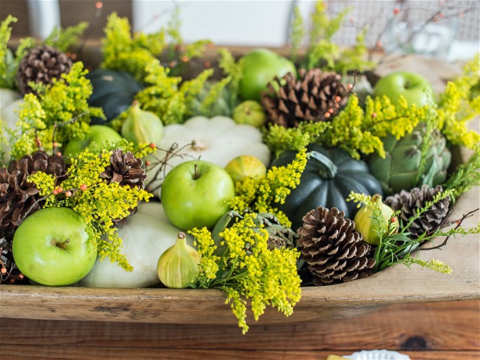 pine cones and green apples, very pale and dark green pumpkins, and tiny yellow flowers, in an oval wooden dish, thanksgiving wishes