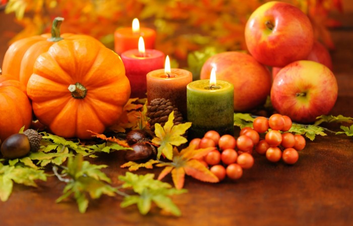 apples and four lit candles, faux pumpkins and fall leaves, conkers and pine cones, thanksgiving messages for friends, red faux berries
