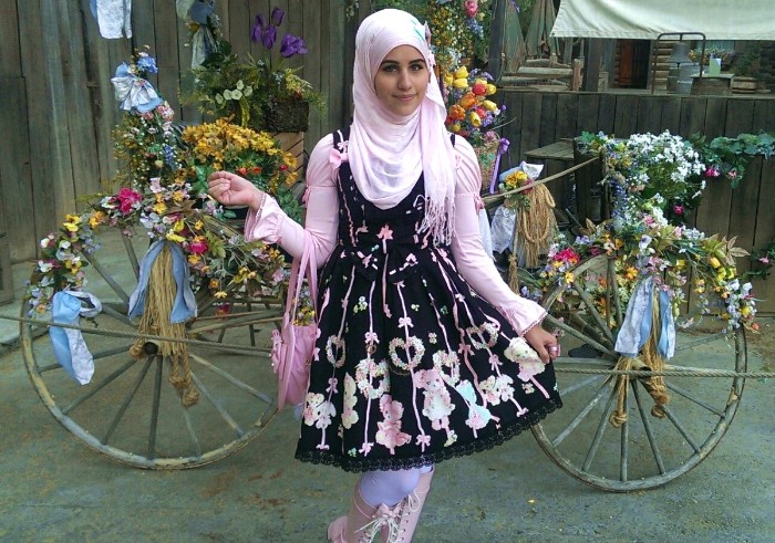 muslim sweet lolita, in a pale pink hijab, wearing a black dress, with a cutesy pattern in pastel colors
