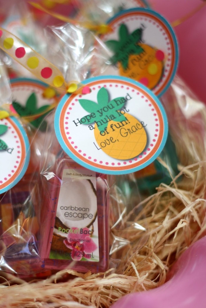 party favor idea, small bottles of coconut body lotion, wrapped in clear plastic, and decorated with a round label, featuring a pineapple, and the words hope you had a hula lot of fun, 50th birthday themes, hawaiian luau party