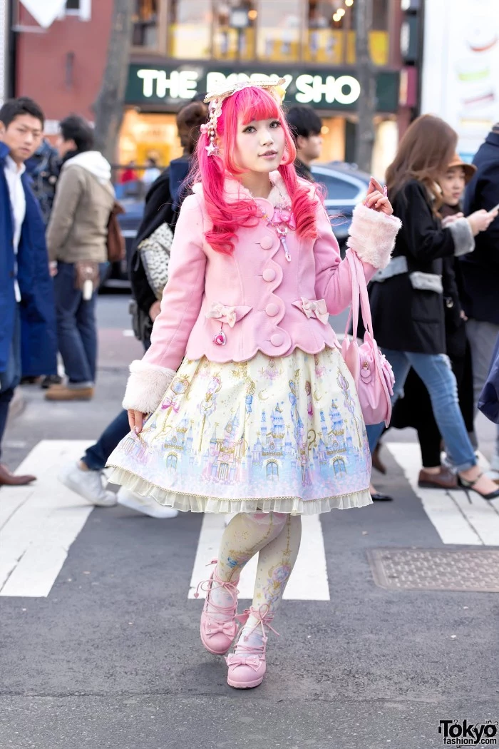 pastel pink lolita fashion coat, with faux fur trims, on a girl wearing a hot pink wig, and a cream dress with light blue motifs