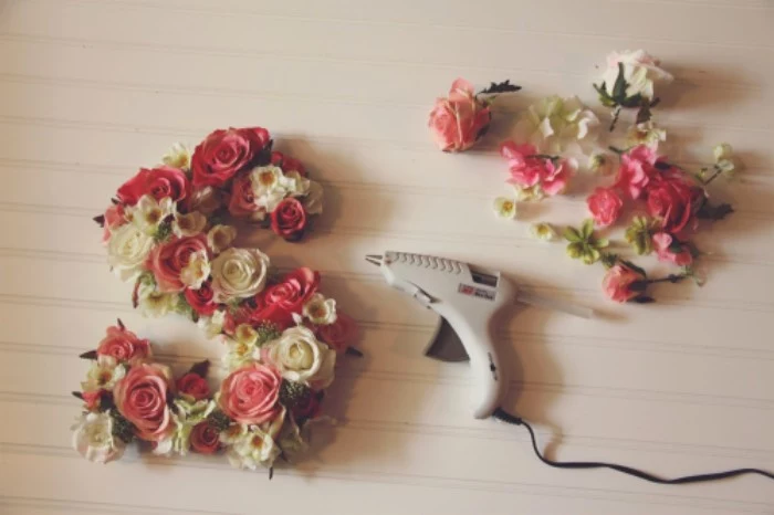 the letter s, decorated with faux roses, in pink and cream, and small fake white and yellow blossoms, teenage girl room ideas, light grey glue gun, and more fake flowers nearby