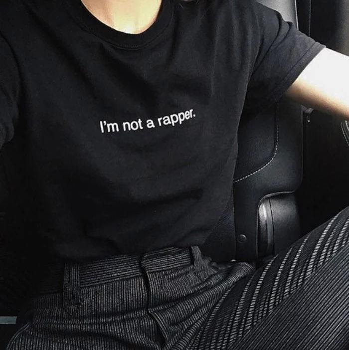 pinstriped trousers in black and white, and a black t-shirt with the words, i'm not a rapper, printed in white, worn by a slim woman