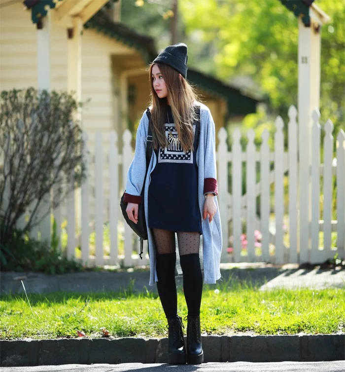 over-the-knee socks in black, worn with sheer black patterned tights, a dark grey jumper mini dress, black combat boots, and an oversized pale blue cardigan, 90s grunge fashion, on a slim young woman, with long brunette hair, and a grey beanie hat