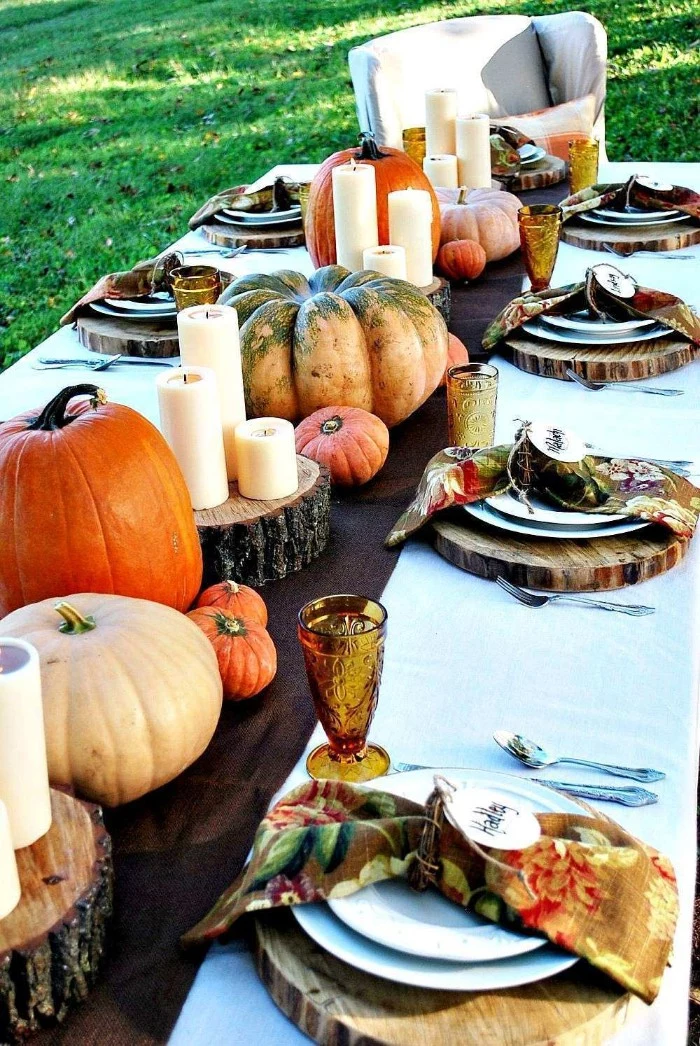 grassy lawn near a thanksgiving table, with round natural wood place mats, candles and assorted pumpkins