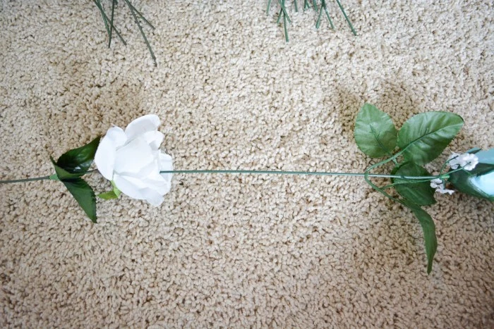 diys for girls, two fake roses, in white and pale blue, with long plastic stems, stuck together, to form a column