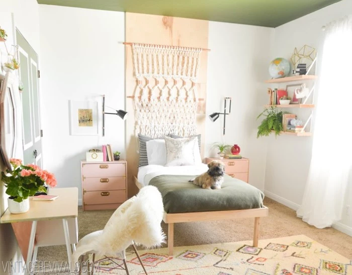 dog laying on a single bed, in a room with white walls, decorated with a peach pink stripe, and a green ceiling, teen bedrooms, window with white curtains, beige patterned rug