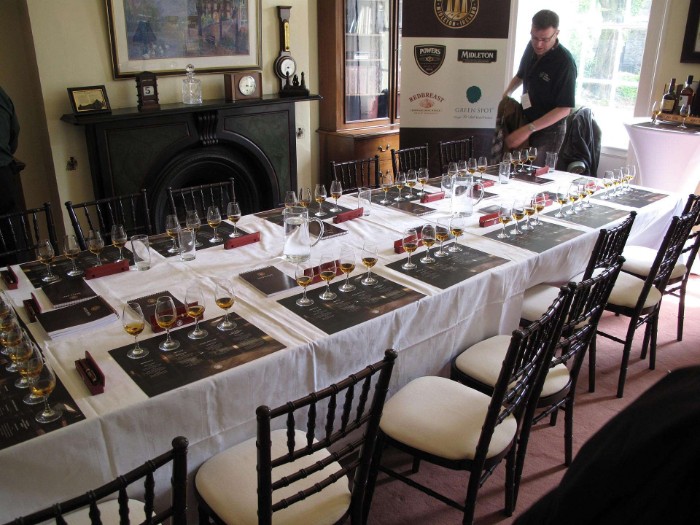 long rectangular table, with several place mats, each containing four glasses, containing some whiskey, 50th birthday celebration ideas for husband, whiskey tasting event