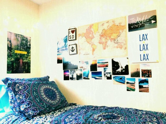 patterned blue bedding, on a single bed, in a room with pale walls, decorated with photos, teenage bedroom ideas for small rooms, posters and a map of the world