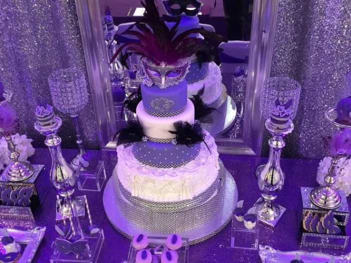 violet masked ball birthday theme, with silver glitter, 50th birthday colors, multi-layered cake, in white and violet, decorated with a venetian mask, and black feathers