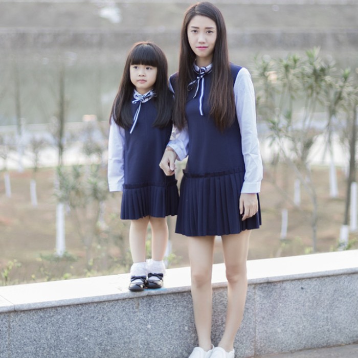 mother and small daughter, wearing the same sleeveless, navy blue dresses, with pleated skirts, over white shirts, with striped blue and white ribbon ties, cute thanksgiving outfits for kids 