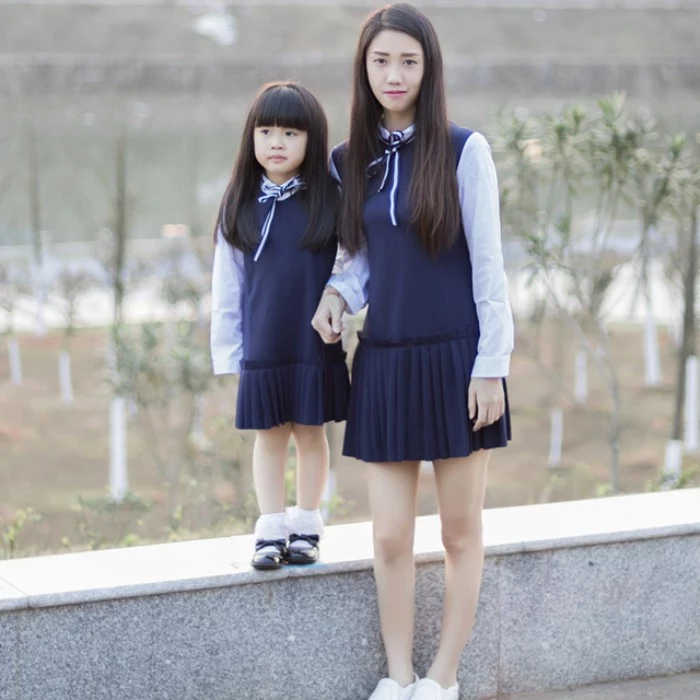 mother and small daughter, wearing the same sleeveless, navy blue dresses, with pleated skirts, over white shirts, with striped blue and white ribbon ties, cute thanksgiving outfits for kids 