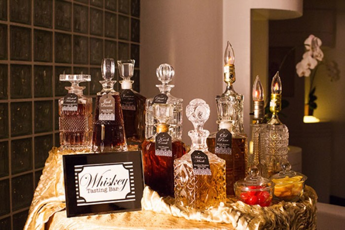 50th birthday celebration ideas for husband, a selection of whiskeys, in different ornamental glass bottles, on a small round table, with a shiny gold tablecloth