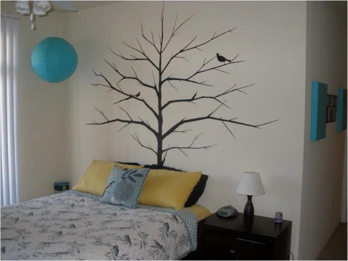 tree with bare branches, and two birds, painted in black, on a pale cream wall, cute teen rooms, bed and a dark brown cupboard