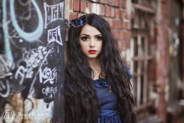 lipstick in red and black eyeliner, on a pale young woman, wearing a blue dress, and a matching blue bow in her hair