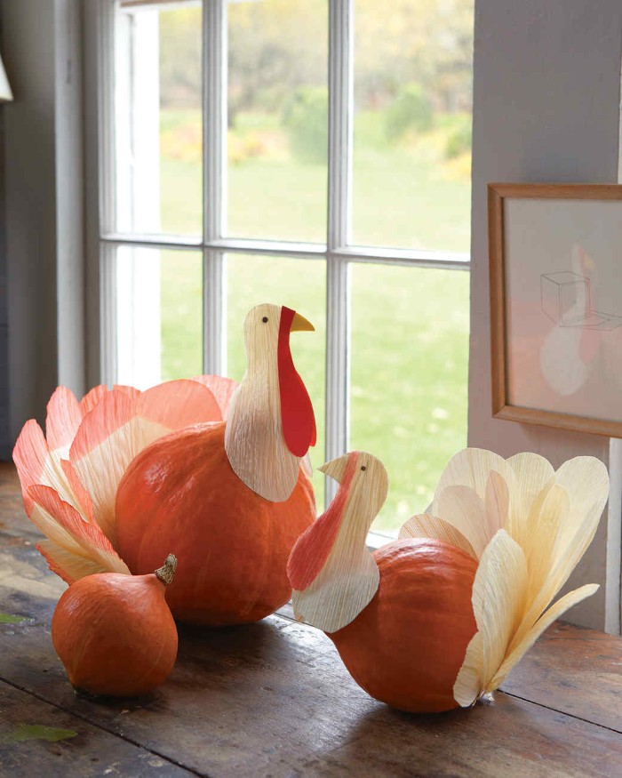 turkey decorations, made from two orange pumpkins, and paper cutouts, placed on a dark brown wooden surface