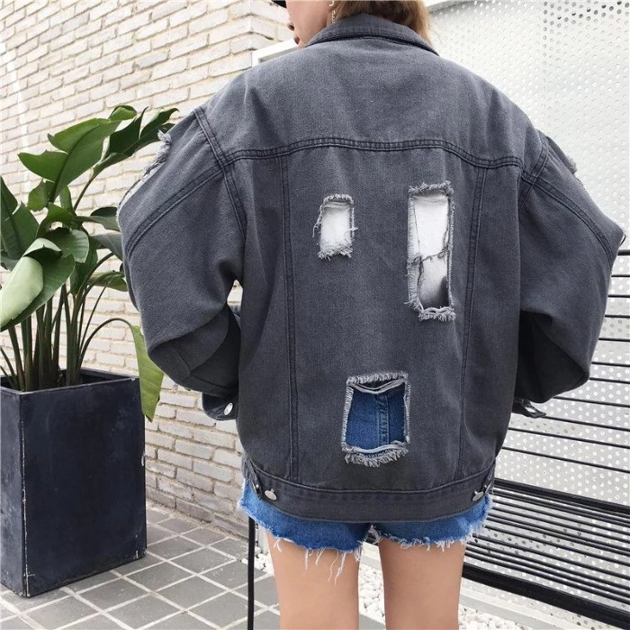 back view of an oversized, grey denim jacket, with three large ripped holes, 90s grunge fashion, worn by a slim woman