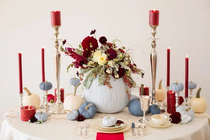 burgundy red candles in different sizes, and small blue faux pumpkins, on a round table, with plates and cups, cheap centerpiece ideas, large light blue hollow pumpkin, filled with burgundy red and cream flowers