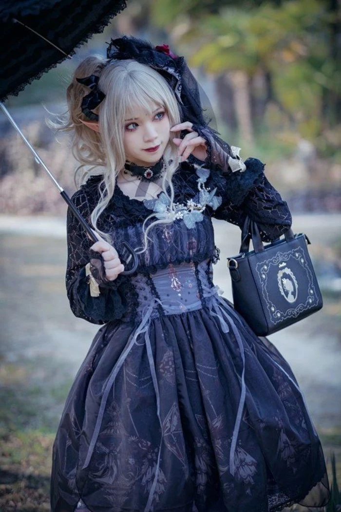 gothic lolita dress in black, worn by a pale girl, with faux elf ears, and a platinum blonde wig