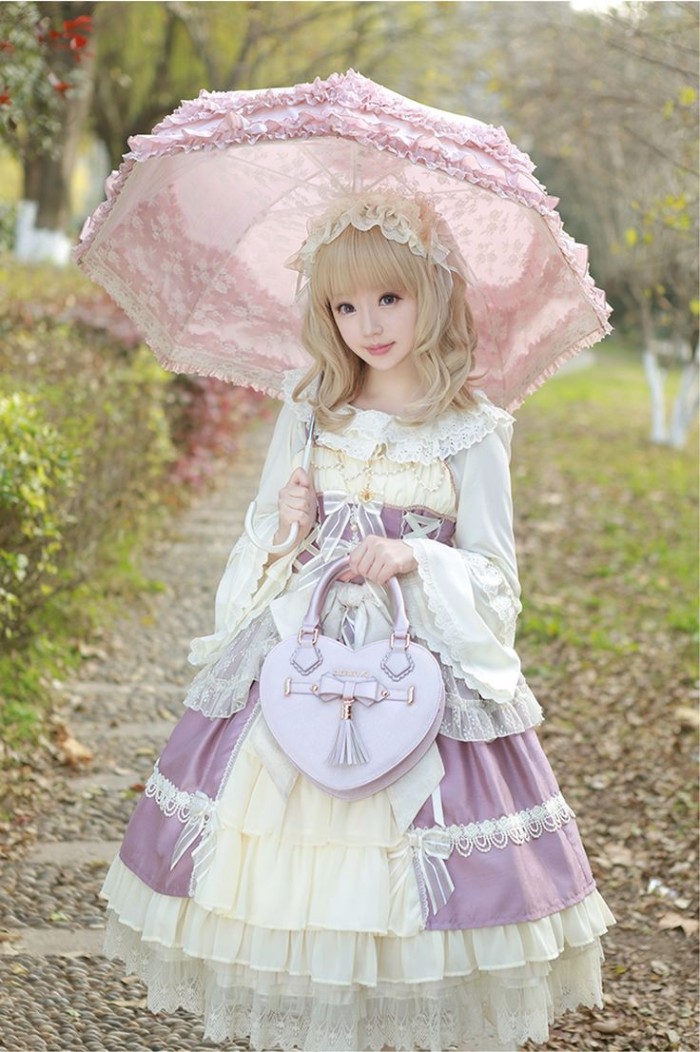 sweet lolita dress, in pale purple, off white and cream, worn by a girl, in a straw blonde wig, holding a pink frilly parasol