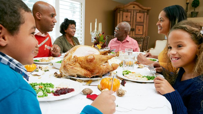 four adults and two kids, sitting around a festive table, thanksgiving messages for friends, roasted turkey and other foods